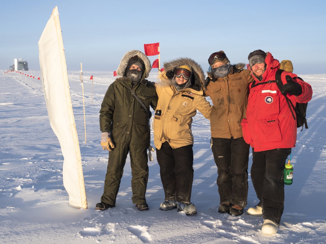 Group shot facing the low sun with the IceCube Lab in distant background.