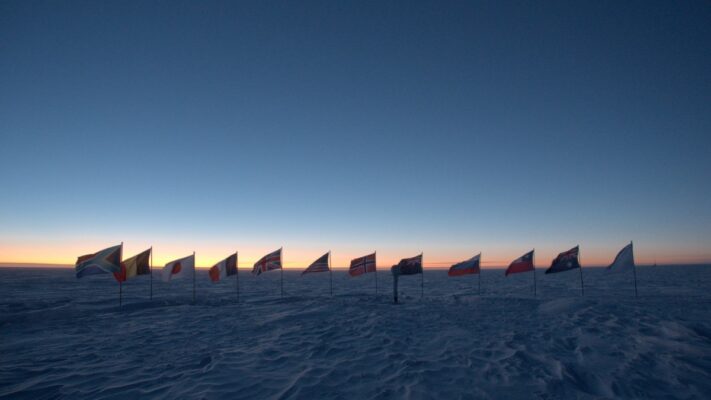 The flags at the ceremonial pole shown in shadow against a colorful horizon.