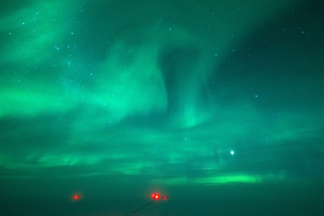 Sky and surface all bathed in green light from auroras.