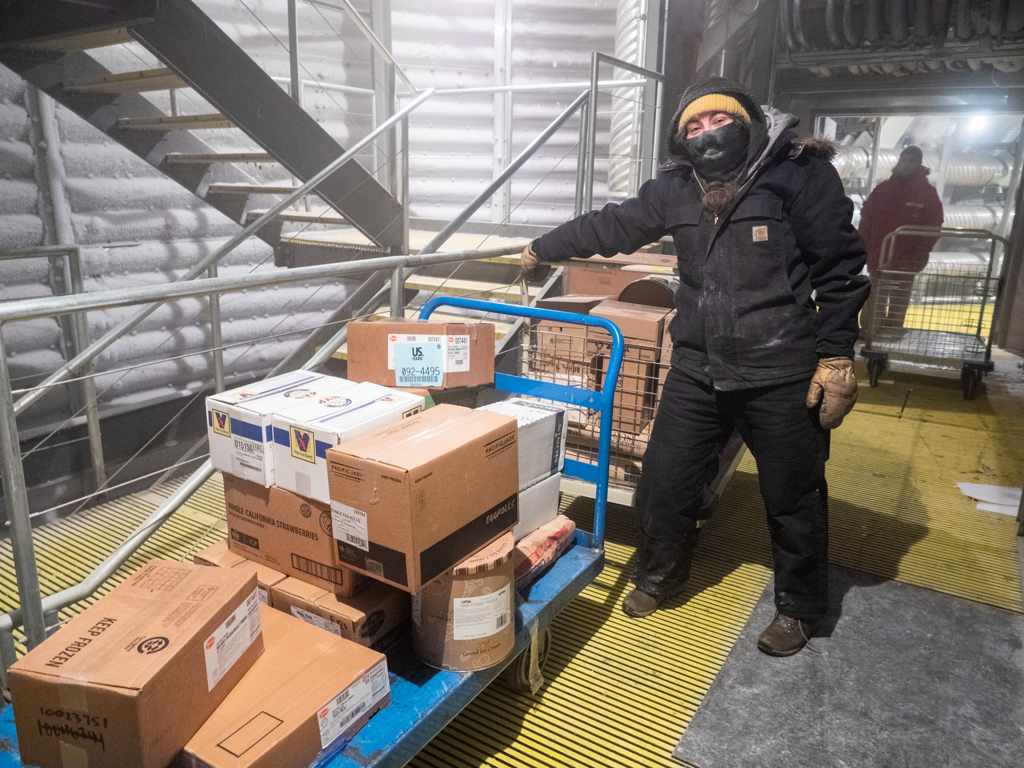 Person standing next to flatbed piled with boxes.