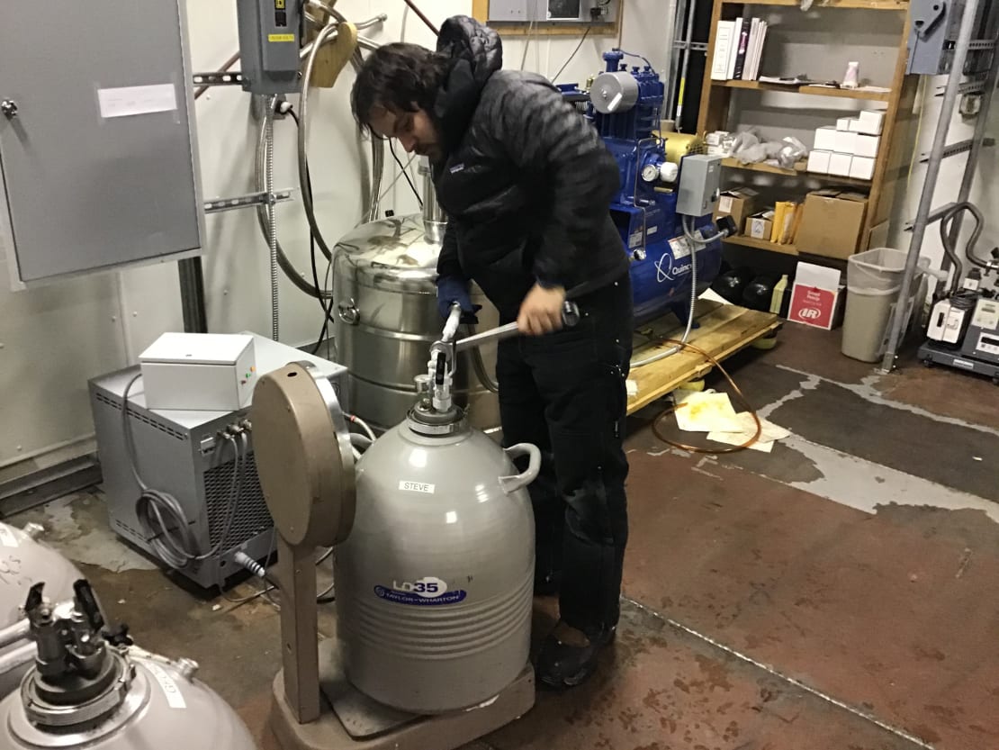 Person removing hose from large metal container.