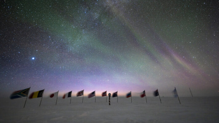 Early sunrise behing the flags at the ceremonial South Pole.