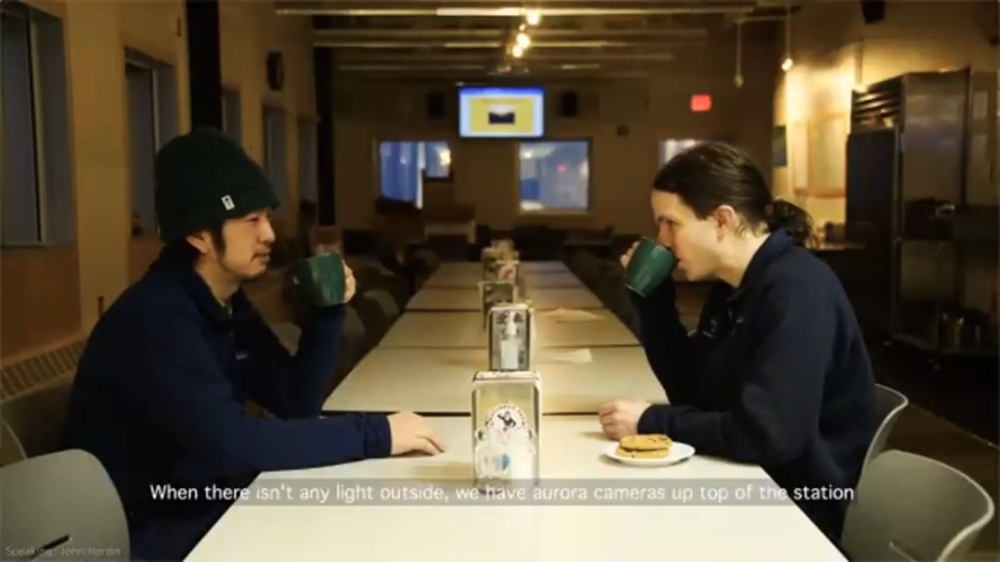 Two men sitting at a long table in the South Pole station galley.