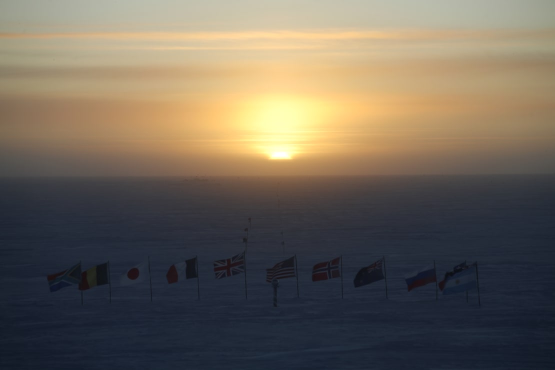 Sun setting over the line-up of flags at the ceremonial South Pole.