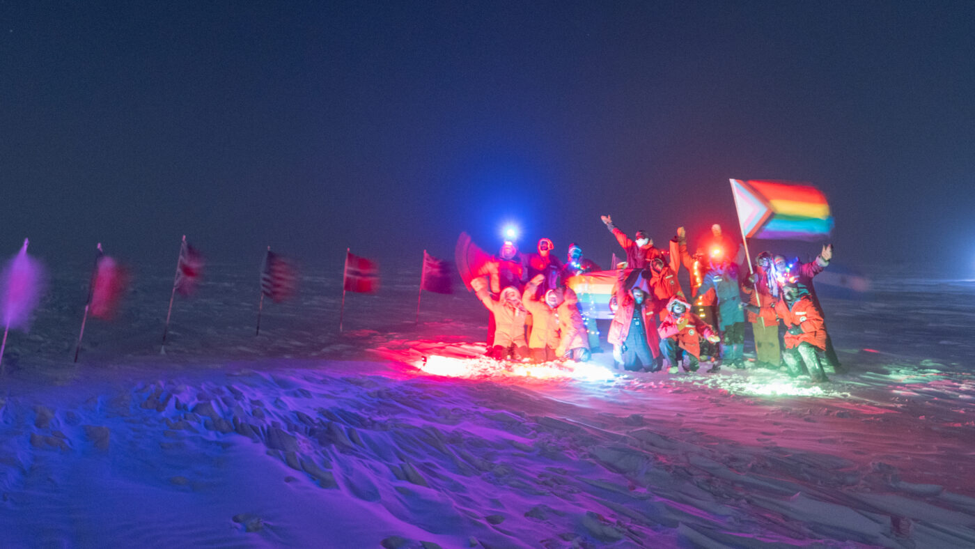 Group photo with Pride flag at ceremonial South Pole.