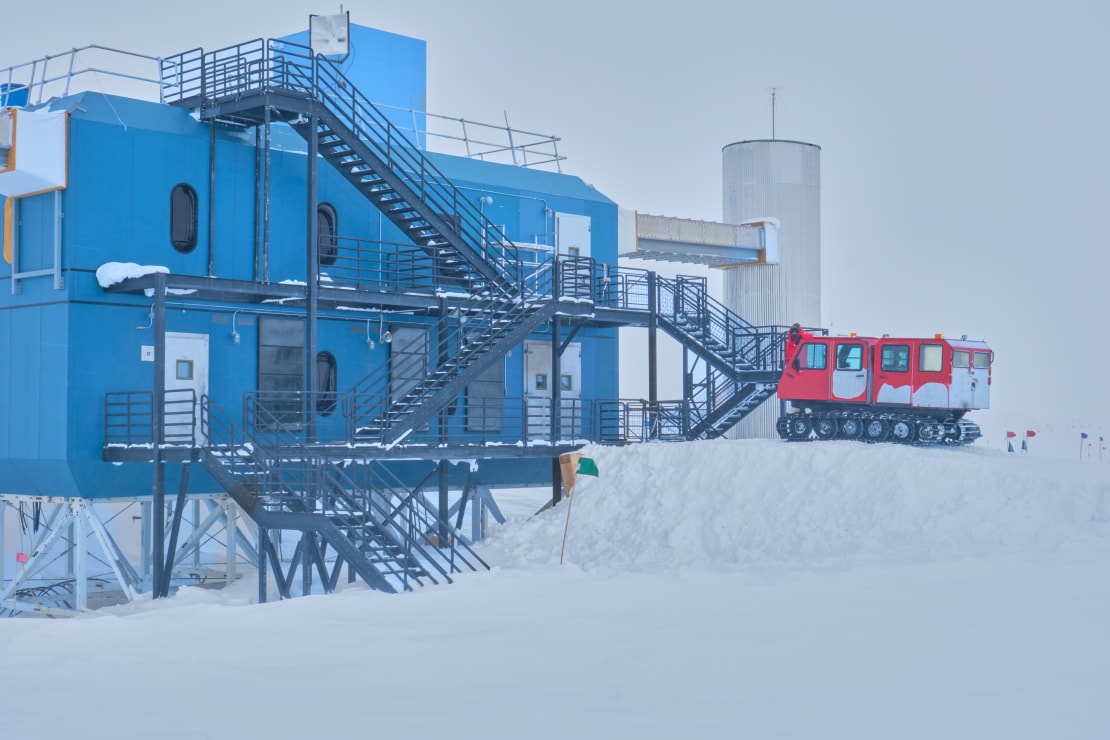 A snow vehicle parked on tall snow ramp up to the IceCube Lab.