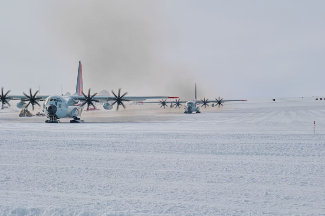 Two propeller planes parked on the ice at the South Pole.