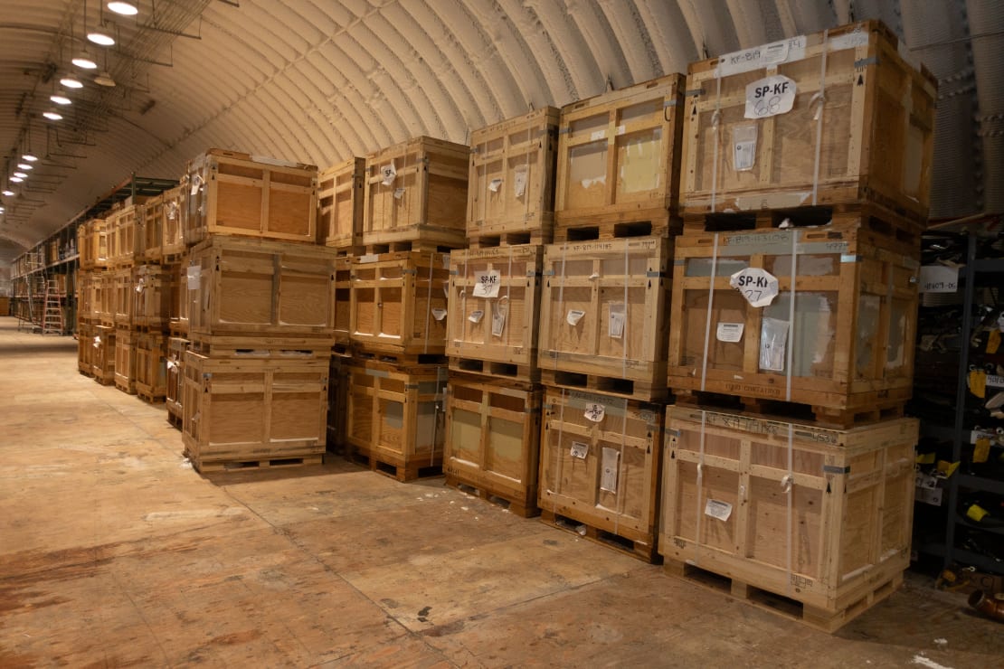 Long line of wooden crates stacked three high on pallets.