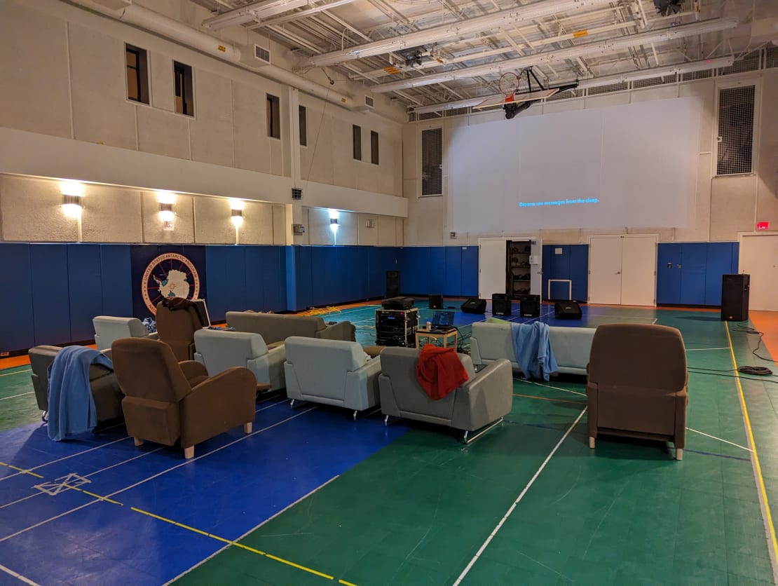 A long view of gymnasium set up with lounge chairs and sofas for movie viewing.