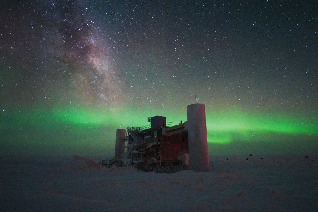 Bright green swath of auroras low in the sky behind the IceCube Lab.