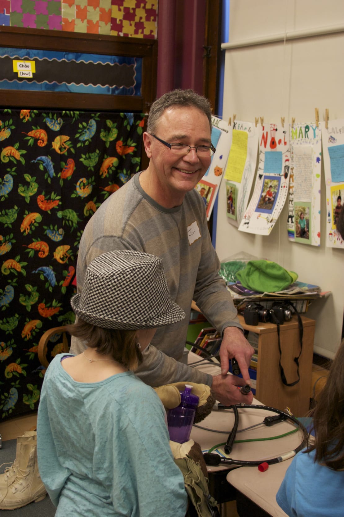 A man smiling and holding a cable next to a kid