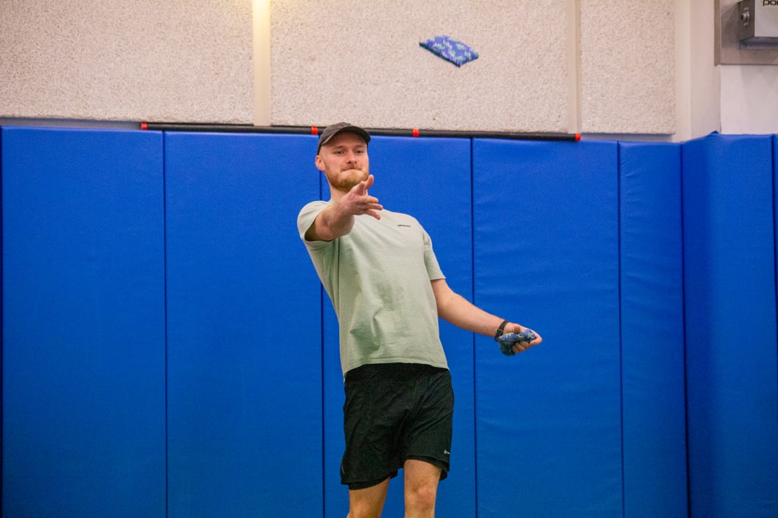 Person tossing a bean bag.