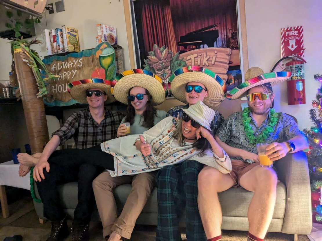 Group of five seated on sofa for group photo, dressed in summer/beach themed attire.