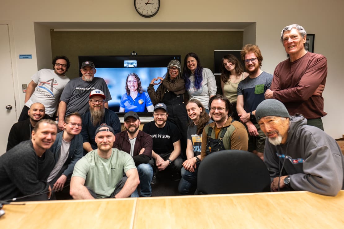 Group photo gathered around astronaut Christina Koch on monitor during teleconference call at South Pole.