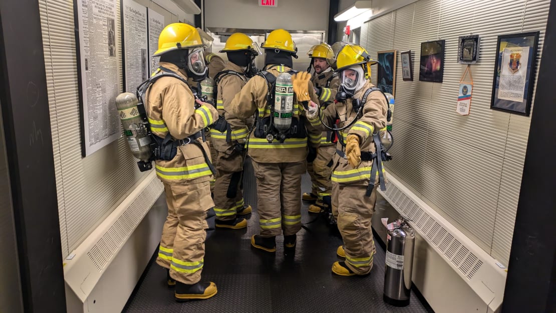 Group in full firefighting gear in the hallway.