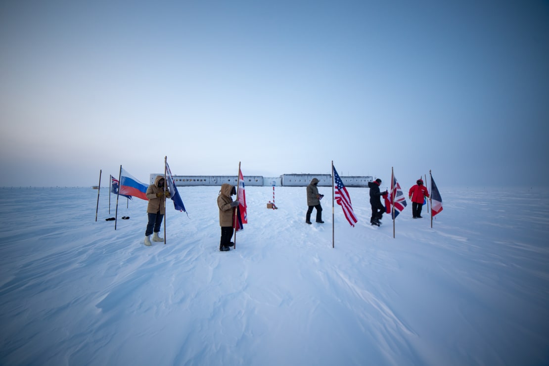 Several people out removing flags at the ceremonial South Pole.