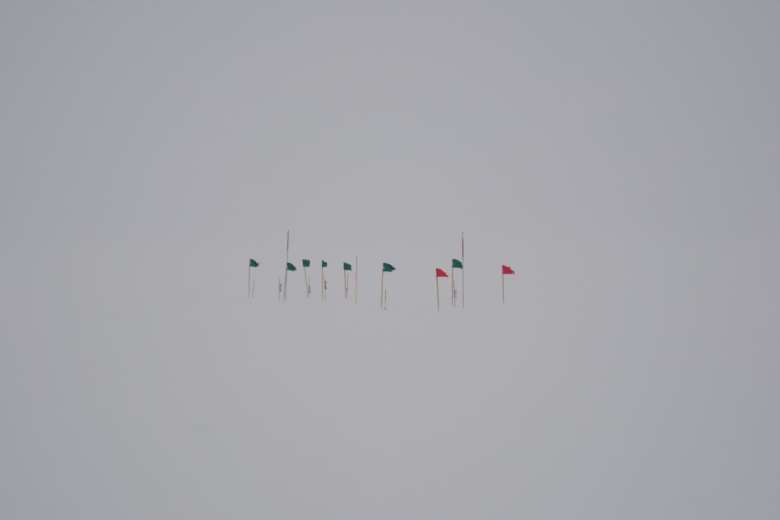 A cluster of flag at the South Pole during poor visibility, all white background.