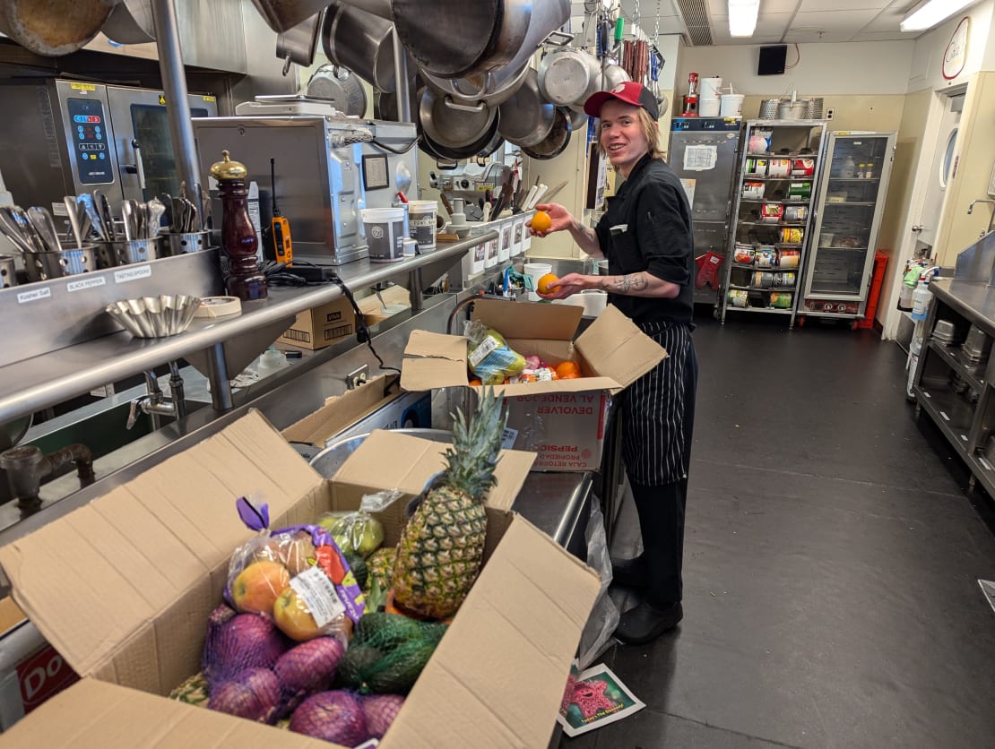 A person unpacking boxes of fresh fruits and vegetables in the South Pole kitchen.