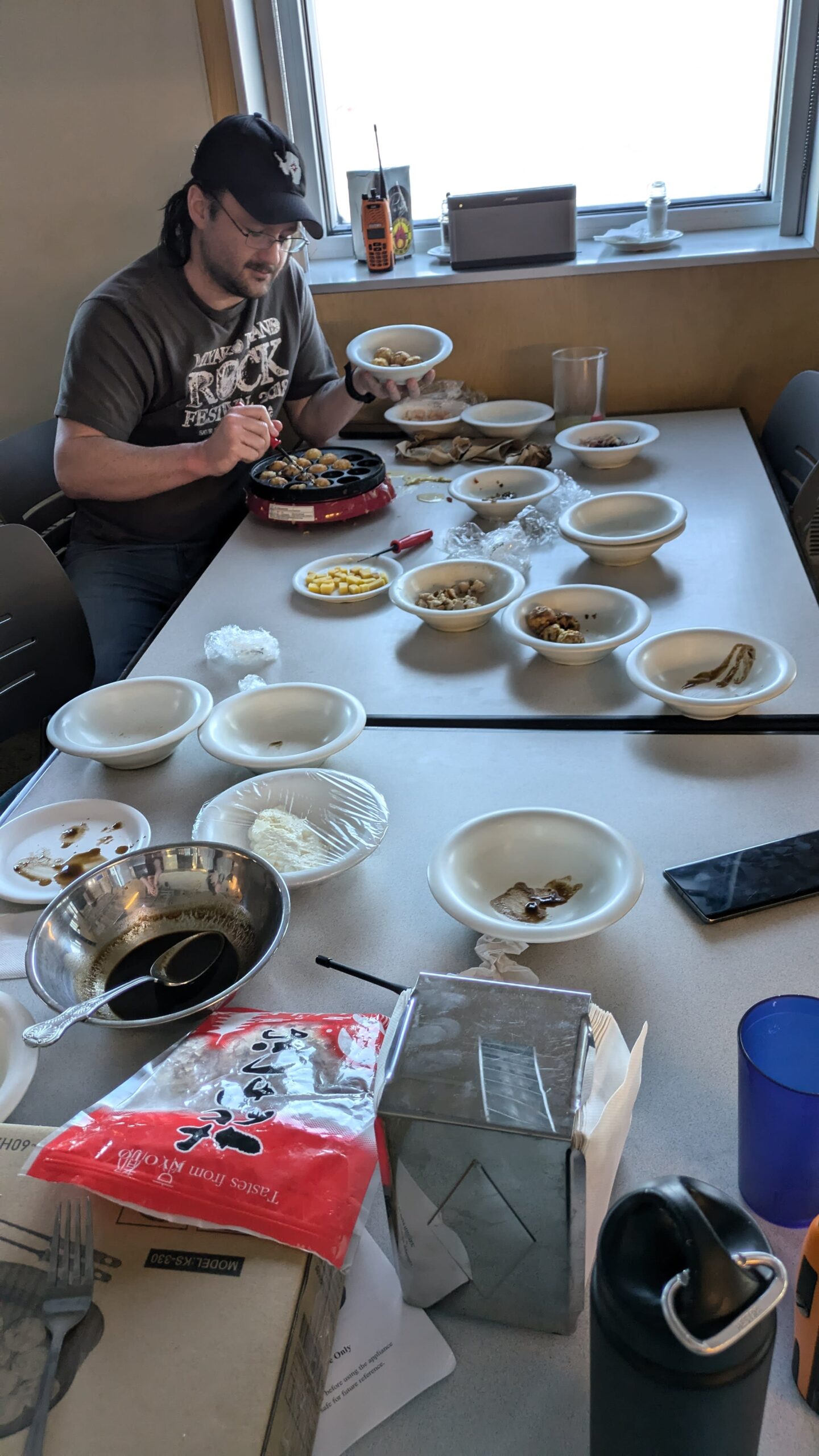 Person seated at long table with lots of bowls, working on special food preparation.