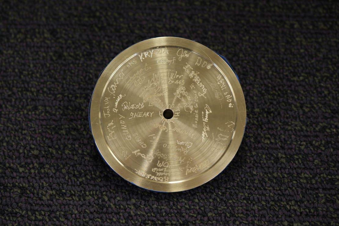 Close-up on circular metal piece with etched signatures.