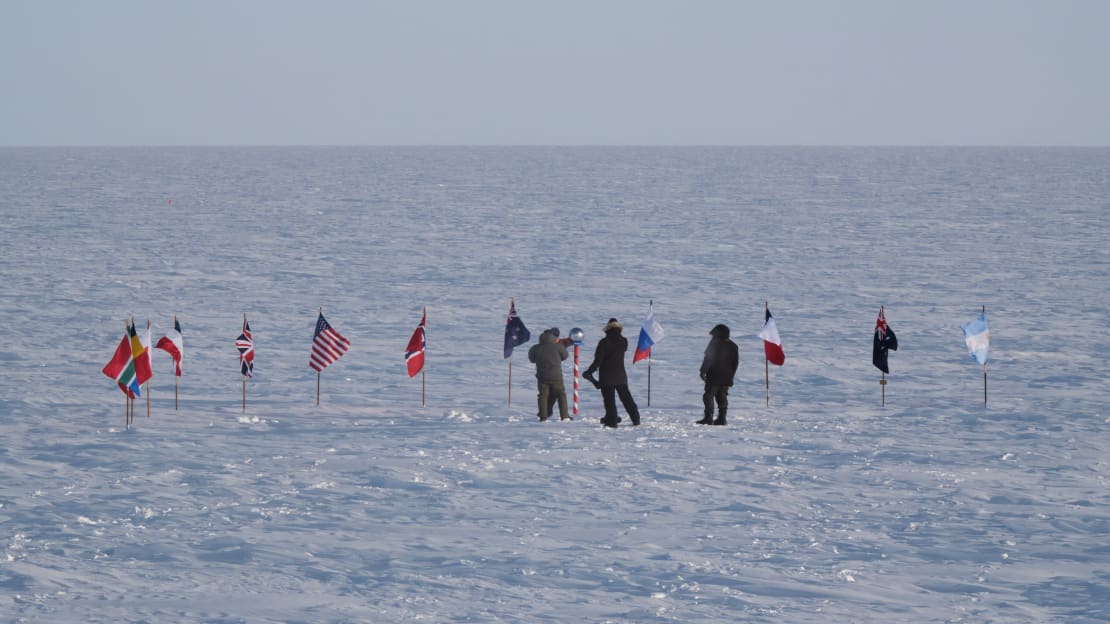 A few people in the distance at the ceremonial South Pole.