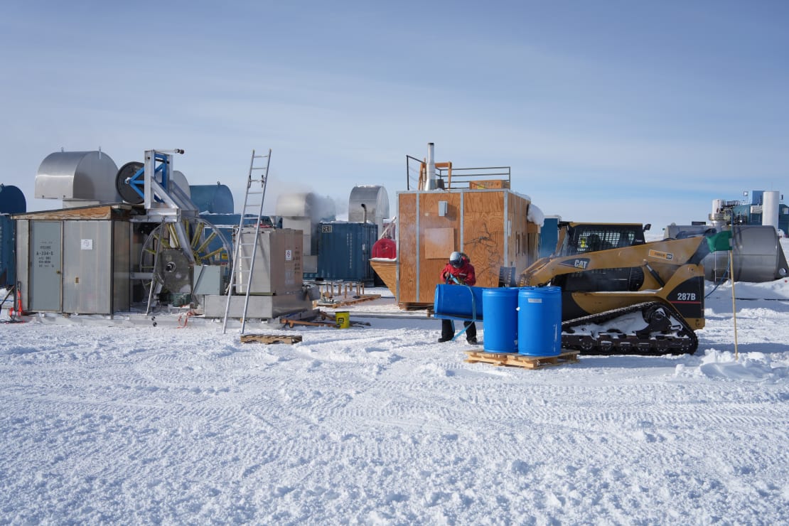 Person working outside at the Pole among containers, crates, palettes, and machinery.