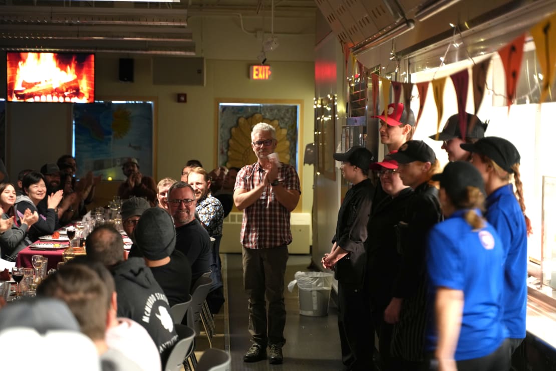 Diners applauding kitchen staff, who are standing off to the right.