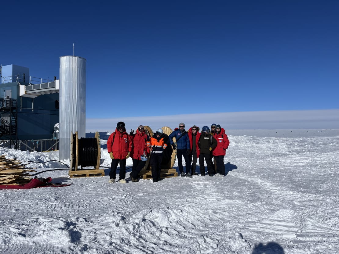 Group photo outside next to IceCube Lab, under clear skies.