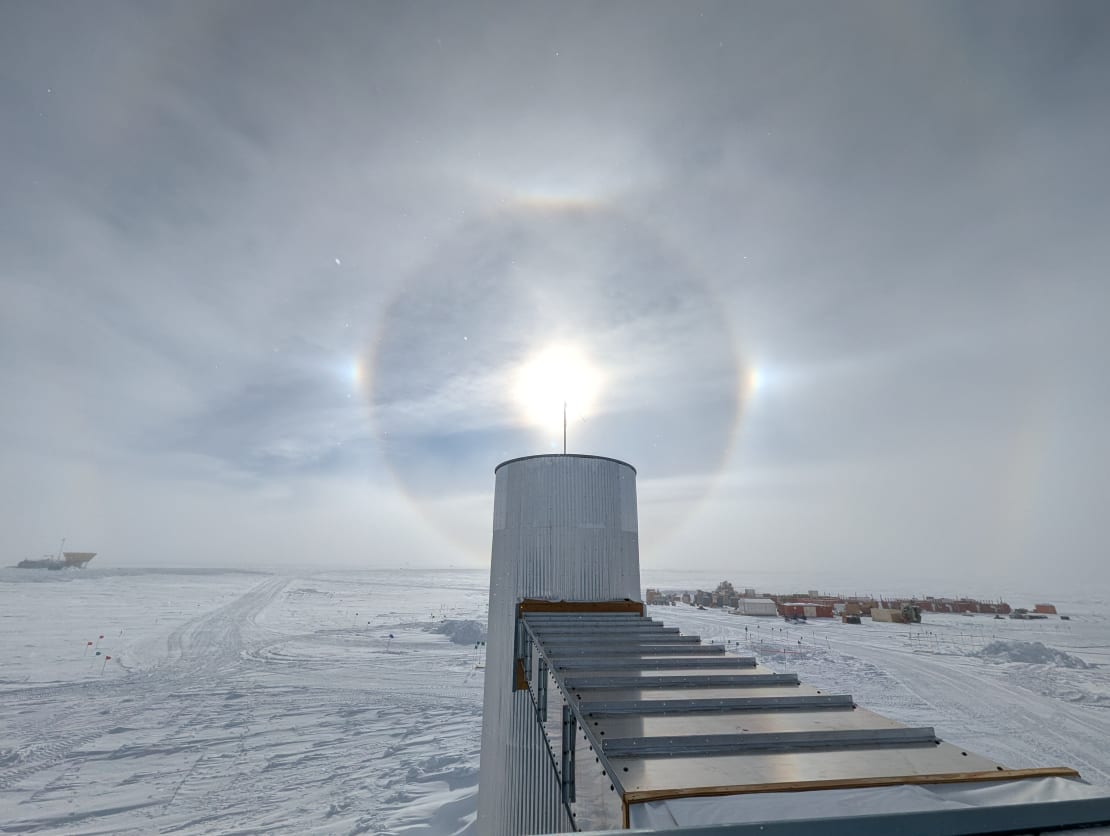 Sun halo with sun dogs centered above one of the IceCube Lab cable towers.