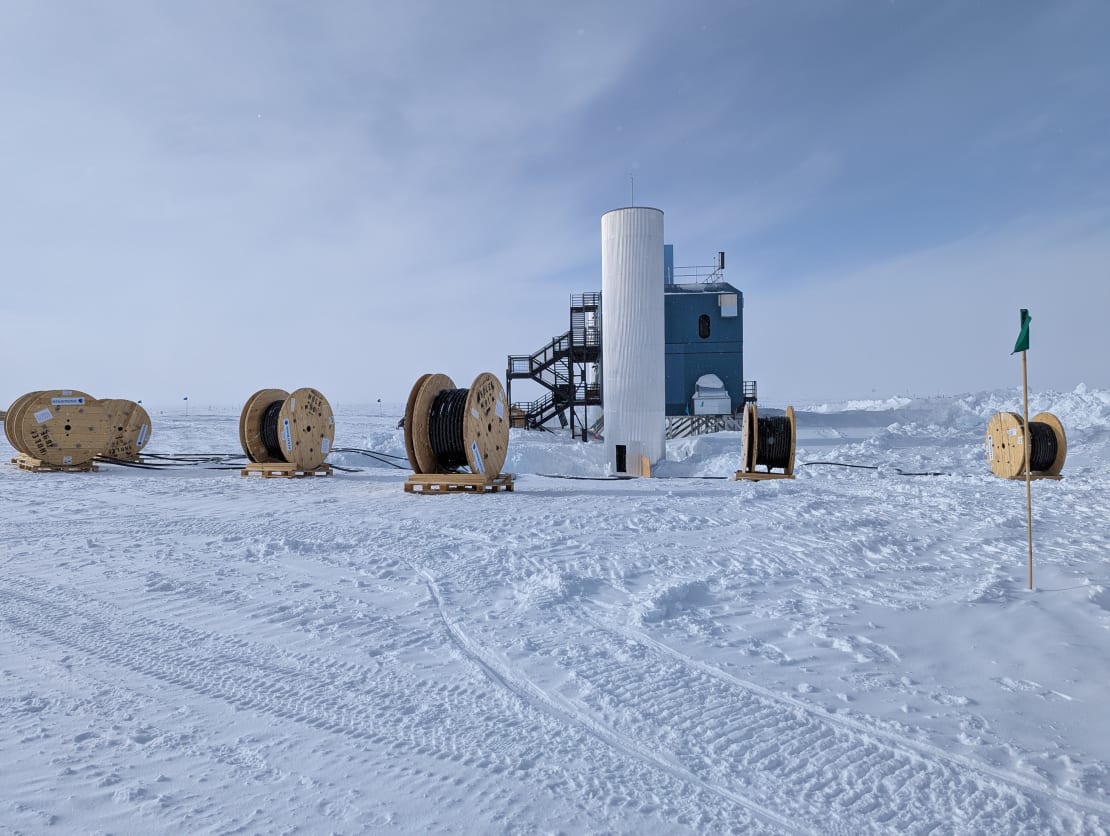 Side view of the IceCube Lab with several large spools of cable in the foreground.