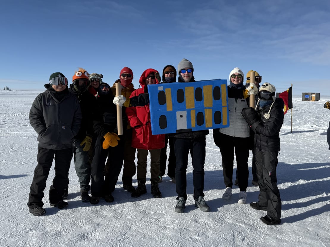 Group of runners posing out on the ice, one in costume as the IceCube Lab.