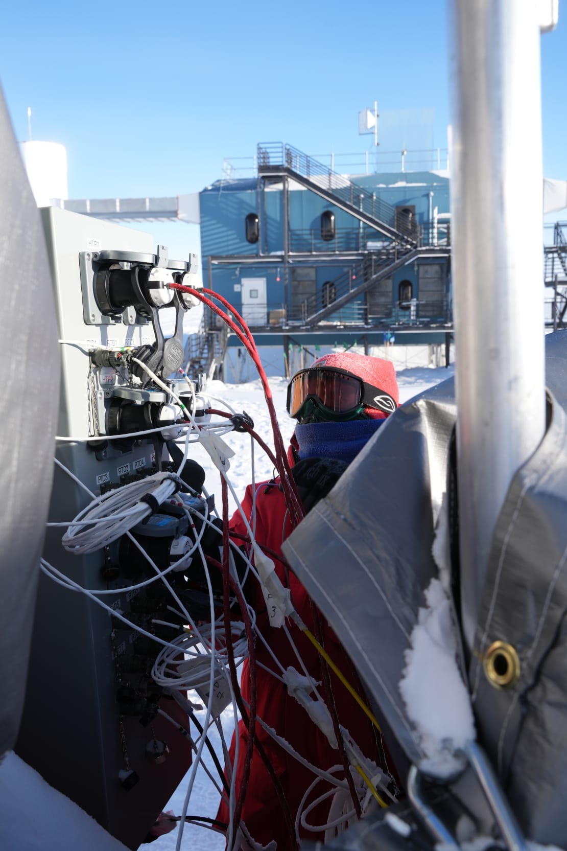 Close-up on winterover working outside in front of the IceCube Lab.