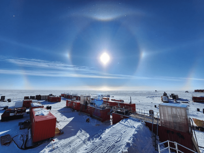 A bunch of buildings with a sundog high in the sky at the South Pole