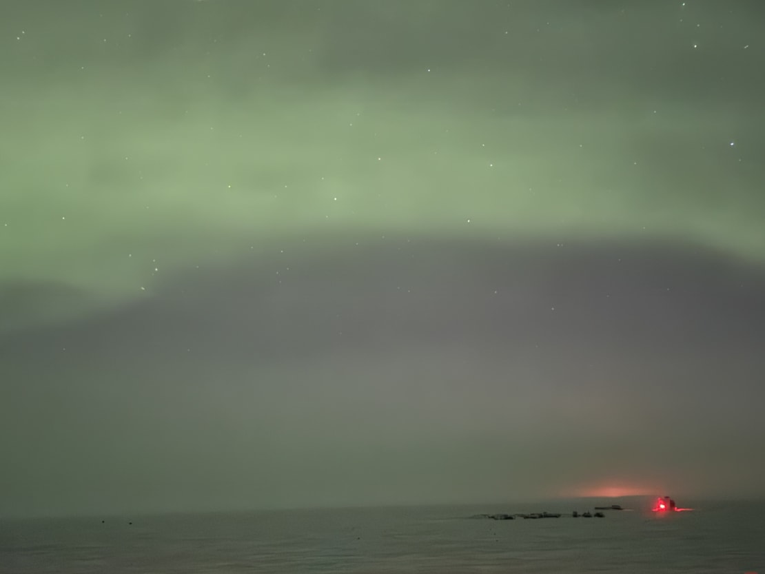The sky lit up with green auroras, appearing less bright with smartphone camera image.