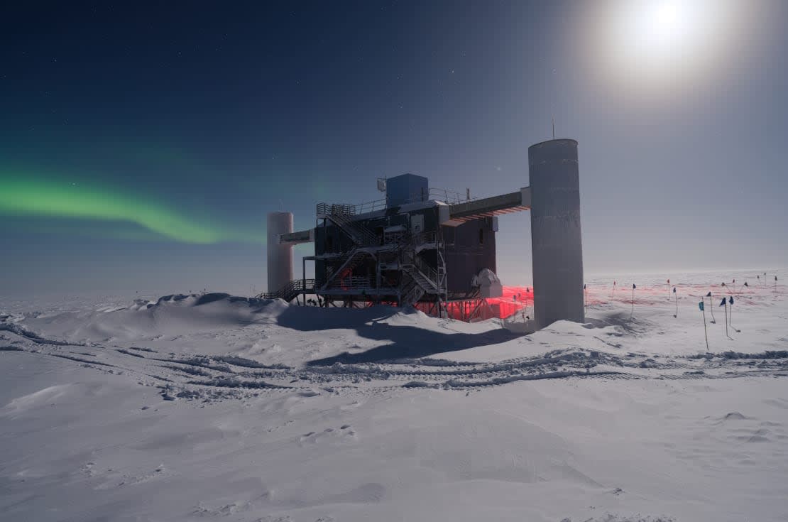 The IceCube Lab under a bright moon with a little aurora in the sky, too.