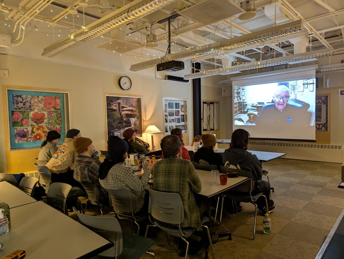 Group seated in front of large screen for video conferencing in South Pole galley.