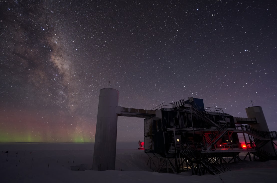 The IceCube Lab in a mostly dark but very starry skiea, showing the Milky Way and some faint low auroras.