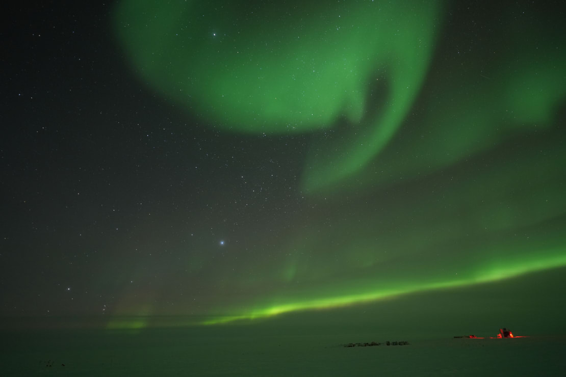 Green aurora formed like a large comma in the sky.