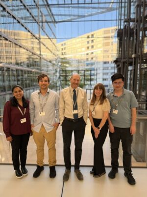 A group of people posing inside of a building with lots of windows