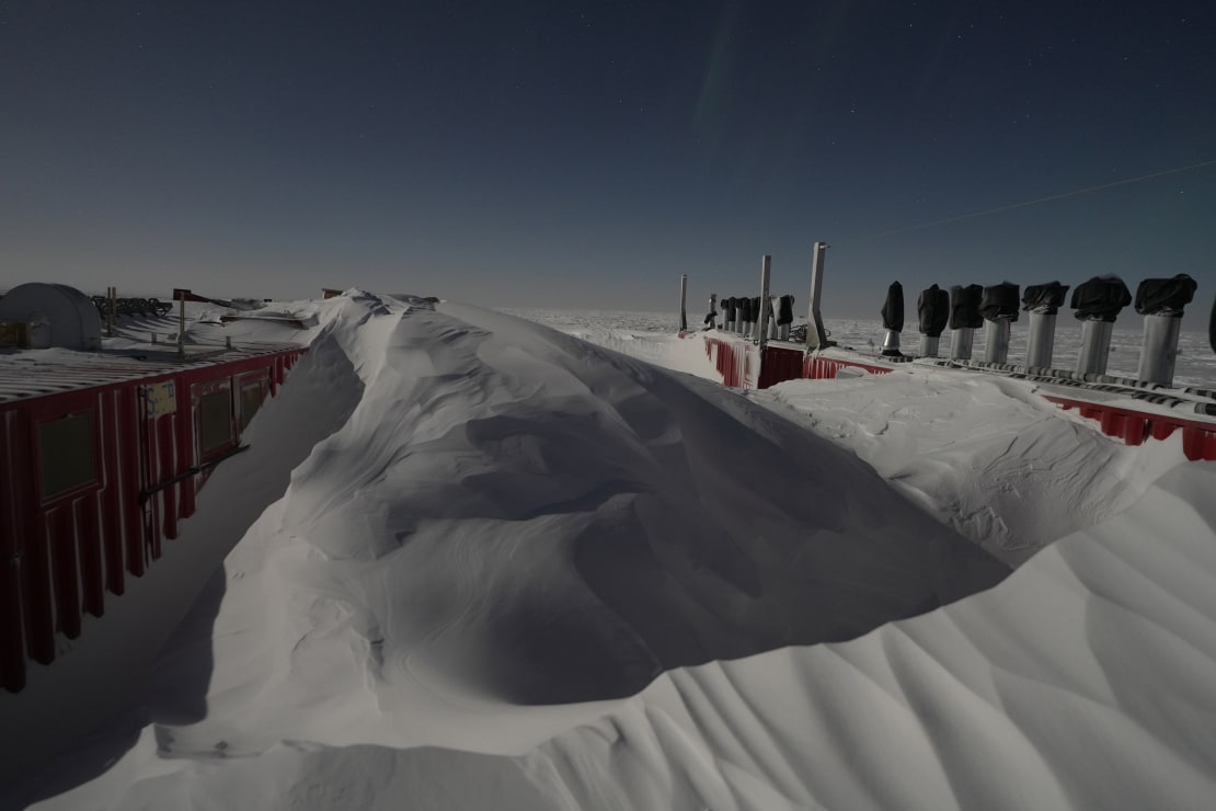 Tall snow piles between outdoor storage containers at the South Pole.