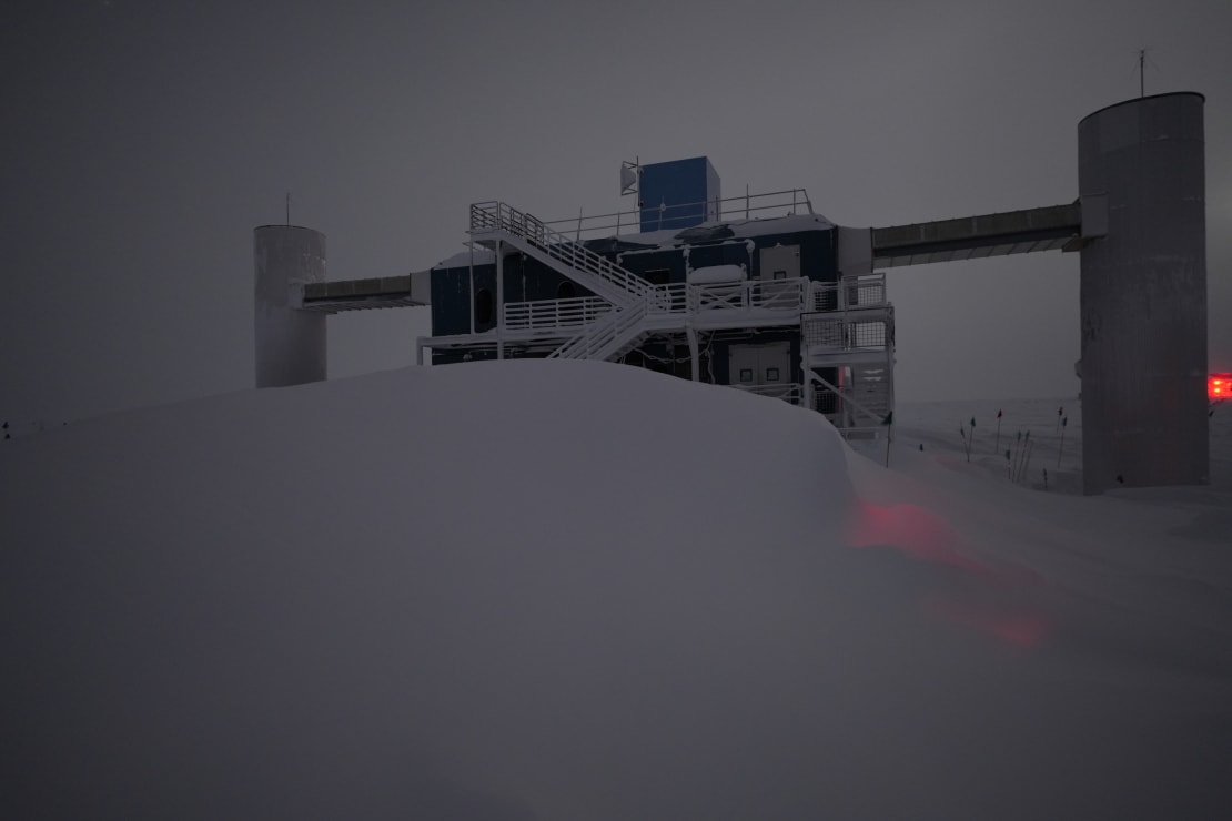 IceCube Lab under overcast sky with large snowdrift in front.
