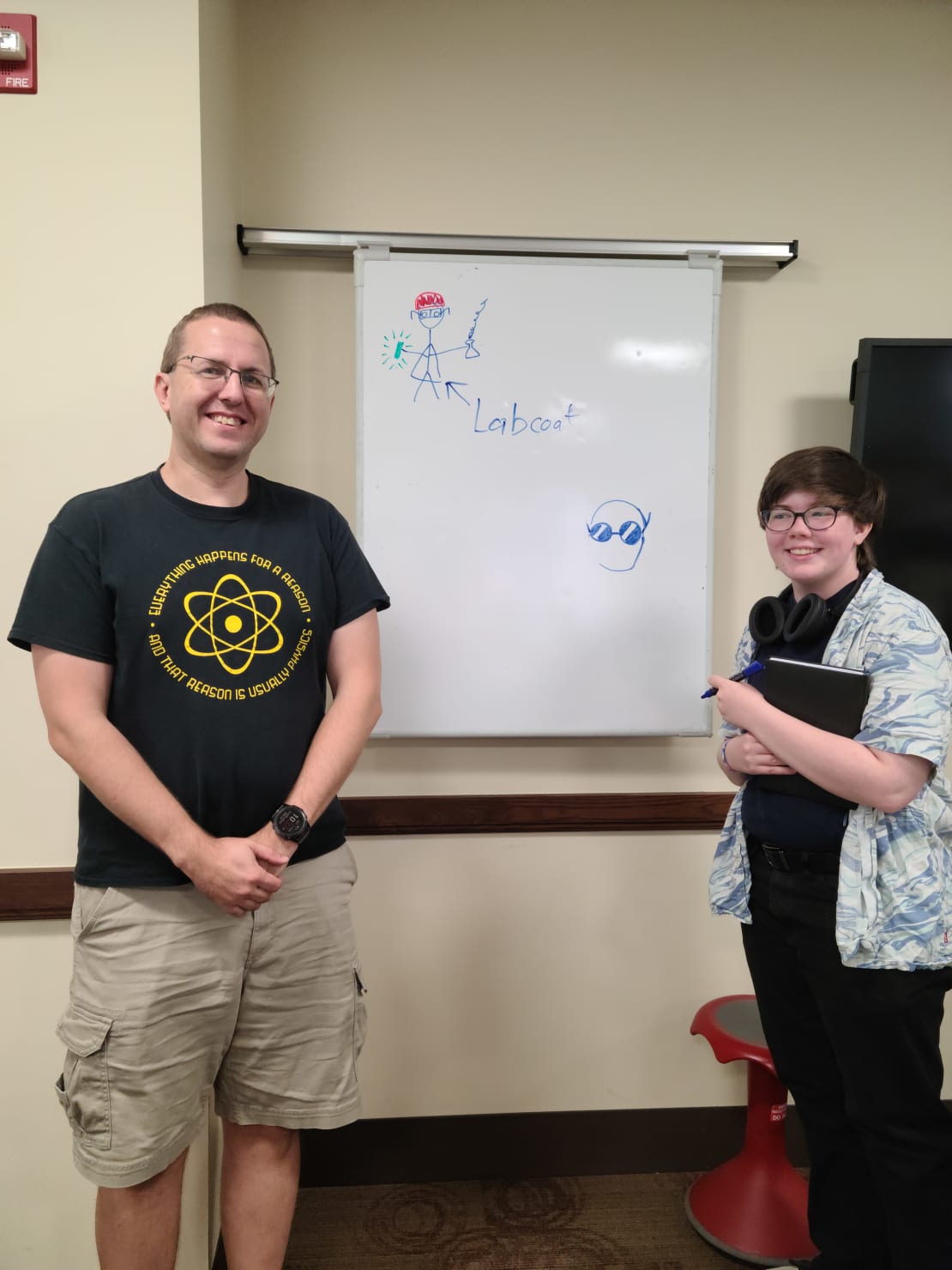 Two people standing next to a whiteboard