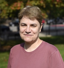 A headshot of a woman in a pink shirt