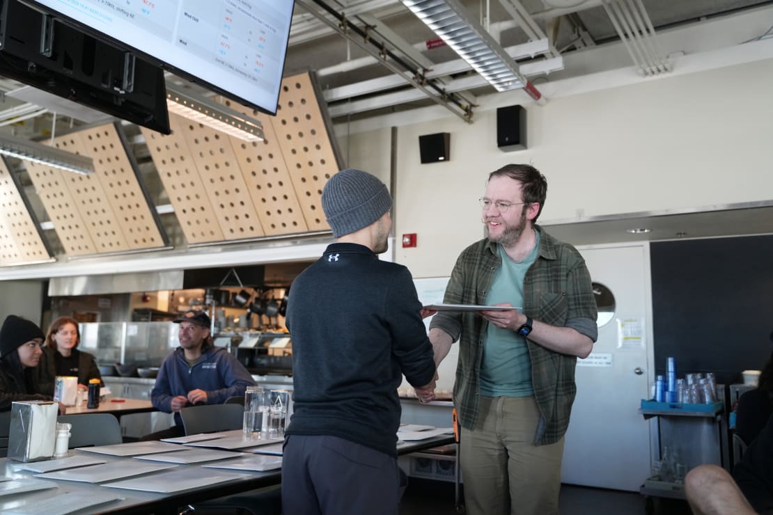 Two people face to face in a handshake and exchange of a certificate.
