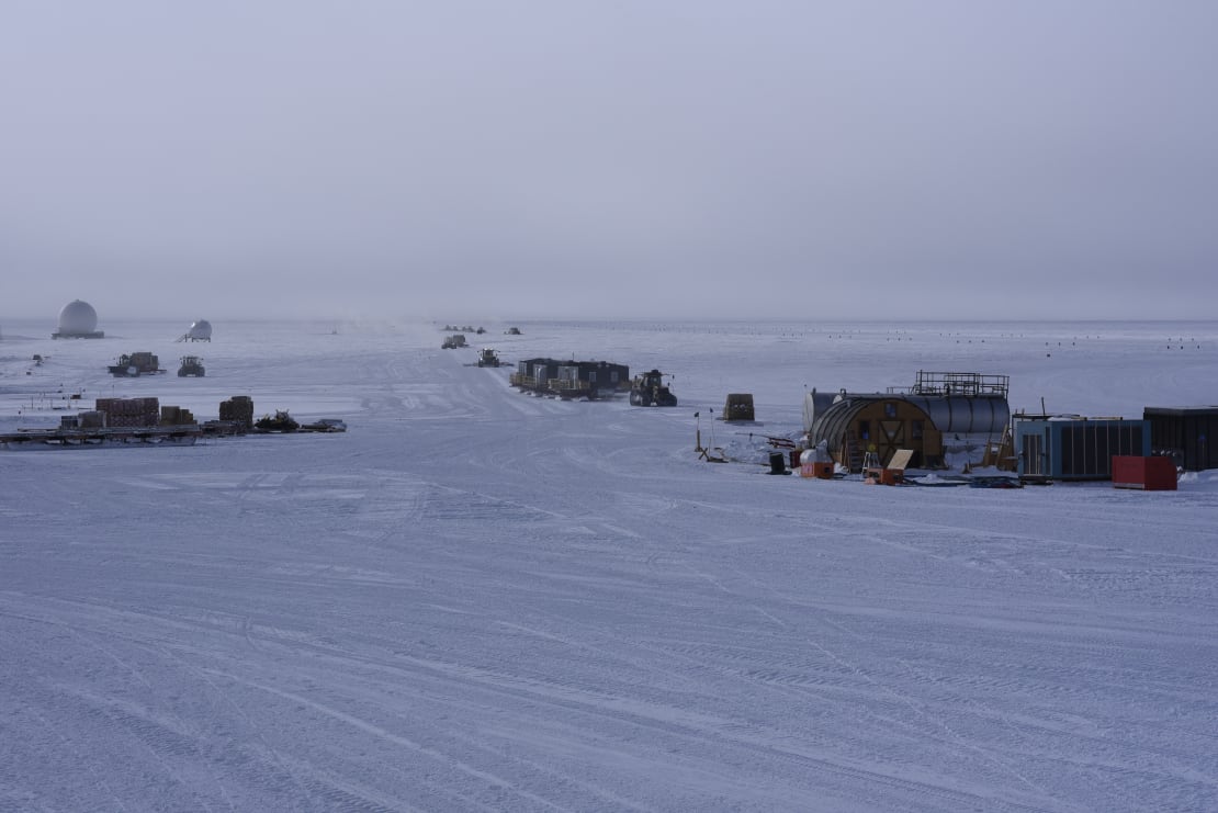 A line of disconnected units of the South Pole traverse parked on the ice.