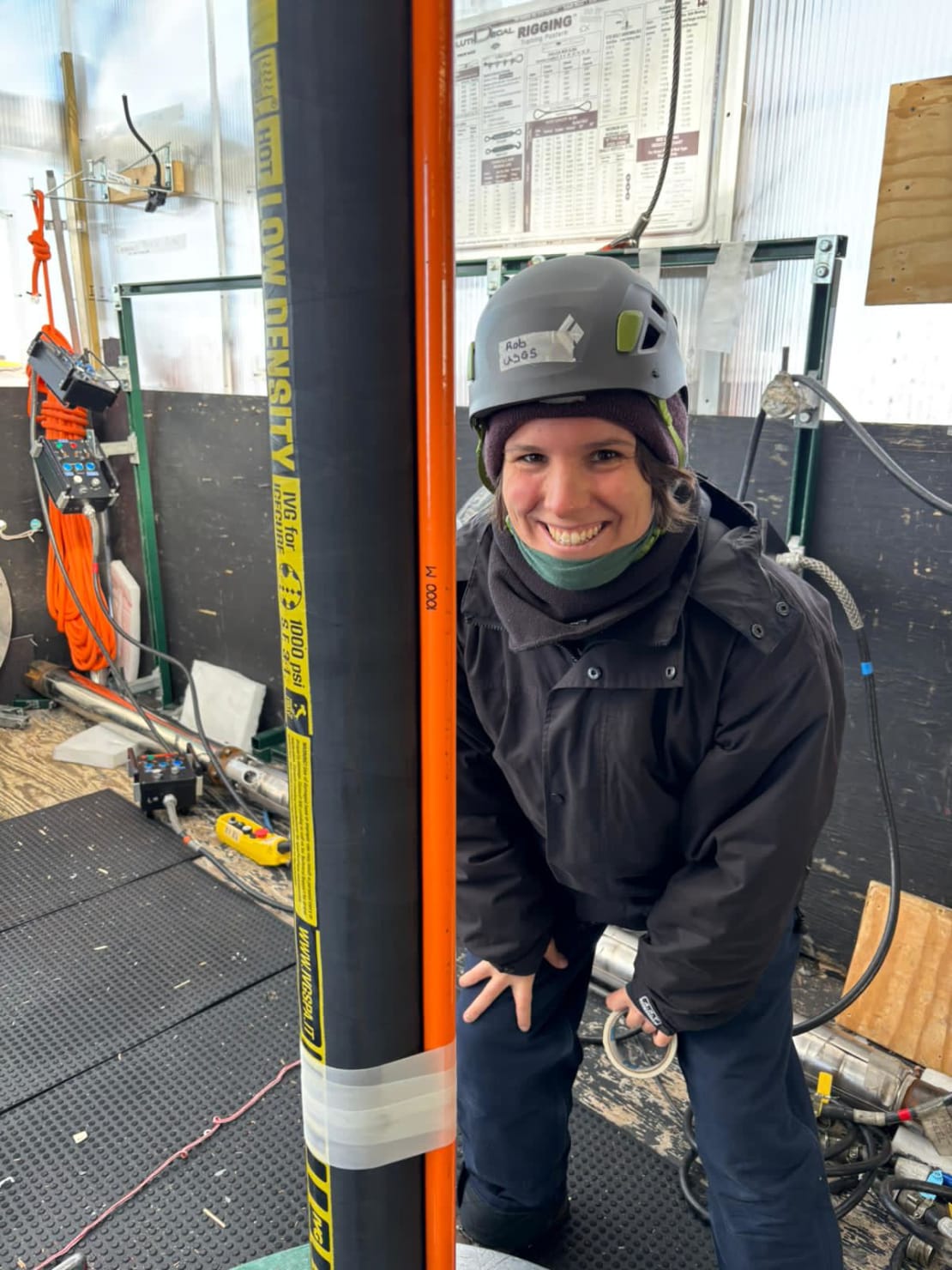 Smiling winterover in hardhat next to drilling cable.