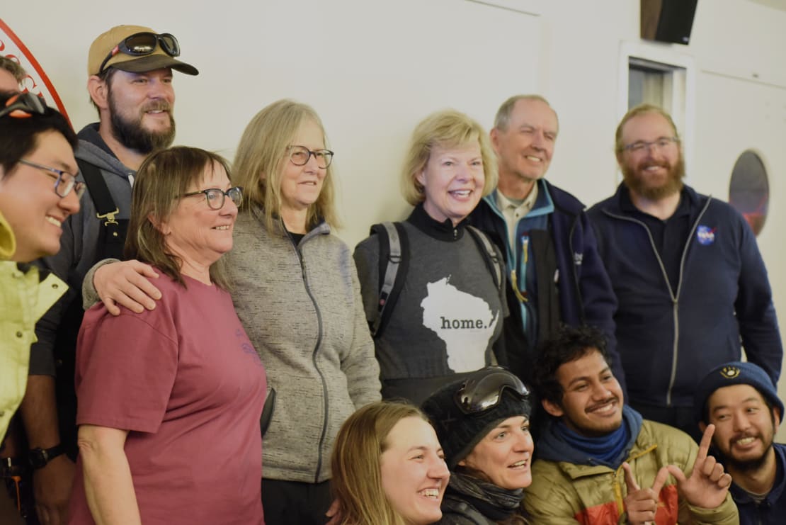 Three-quarter angle view of group photo, back row people standing, front row crouching.