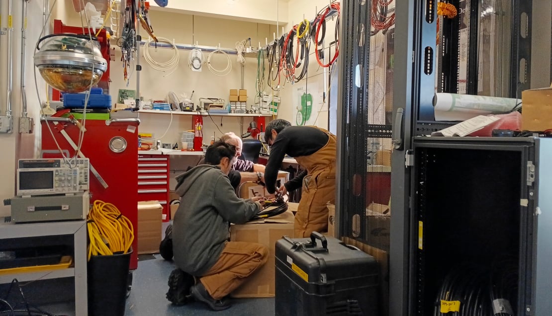 Group crouched together testing cables in the IceCube Lab.