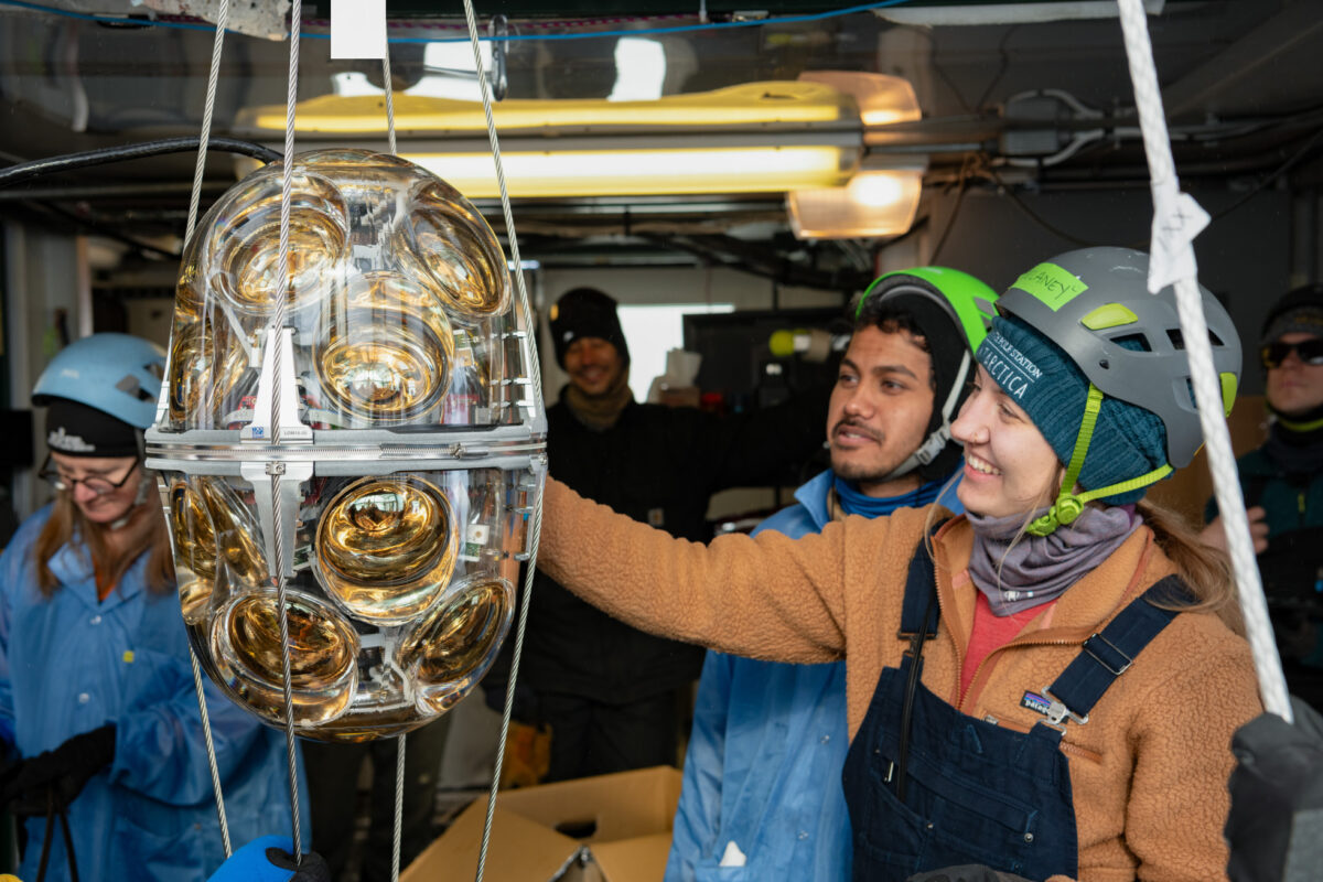 Close-up of a sensor module while it was hanging, a few people nearby looking at it.