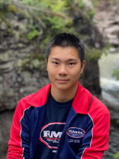 A man in a read and blue sweater smiling.